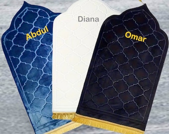 May include: Three prayer rugs with different colored velvet fabric. The rugs are blue, white, and black. Each rug has a gold tassel trim and a geometric pattern. The rugs are labeled "Abdul", "Diana", and "Omar".