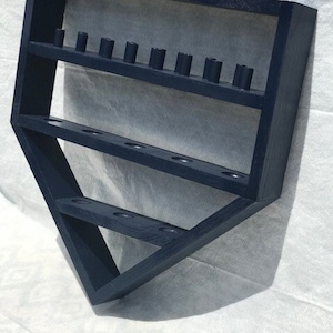May include: A dark blue wooden baseball bat display stand with three shelves. The stand is shaped like a baseball diamond and has holes for holding bats.