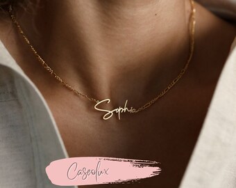 Op de afbeelding: Een goudkleurige ketting met de naam "Sophia" in een cursief lettertype. De ketting heeft een delicaat ontwerp. De afbeelding toont de ketting om de nek van een persoon, met een wit overhemd op de achtergrond.