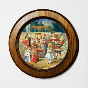 May include: A round wooden framed picture with a colorful illustration of characters from Alice in Wonderland. The Queen of Hearts is yelling at Alice, who is holding a crown. The King of Hearts and other characters are in the background.