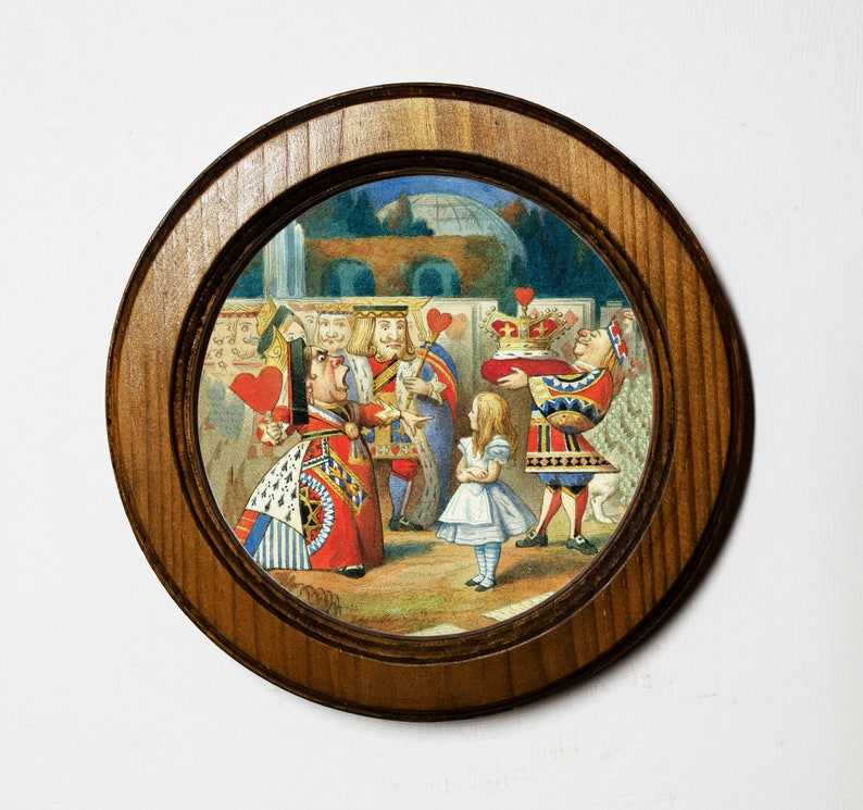 May include: A round wooden framed picture with a colorful illustration of characters from Alice in Wonderland. The Queen of Hearts is yelling at Alice, who is holding a crown. The King of Hearts and other characters are in the background.