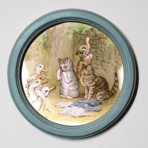 May include: A framed illustration of a scene from Beatrix Potter's The Tale of the Two Bad Mice. Three kittens and two ducklings are depicted in a woodland setting. The kittens are wearing clothes, and the ducklings are holding a pair of trousers.
