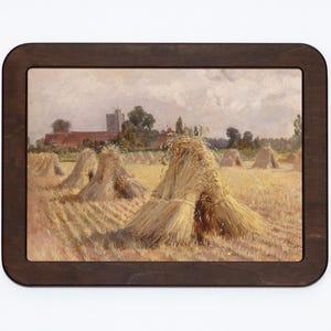 May include: A framed painting depicting a rural landscape with a church in the distance. The foreground features a field of golden haystacks.