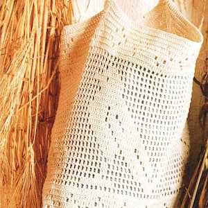May include: Cream-colored crochet tote bag with a rectangular shape and two straps. The bag features an open weave design with small, evenly spaced holes throughout the body. The bag is hanging against a light-colored background.
