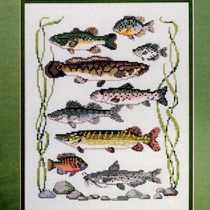 Könnte beinhalten: Kreuzstichmuster mit verschiedenen Fischarten, darunter Barsch, Forelle und Wels. Das Design zeigt detaillierte, pixelige Darstellungen jedes Fisches, wobei Wasserpflanzen und Steine die Unterwasserszene ergänzen. Die Farbpalette umfasst Grün-, Braun- und Blautöne.