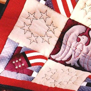 Può includere: Primo piano di una trapunta fatta a mano a tema patriottico. La trapunta presenta quadrati con stelle ricamate, strisce e un disegno di aquila. La tavolozza dei colori comprende rosso, bianco e blu, con un bordo cucito.