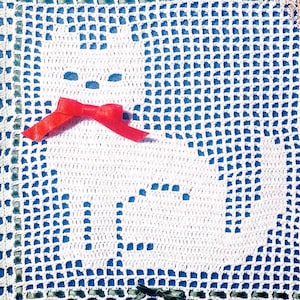 May include: White crocheted doily with a blue border and a red bow in the center. The doily features a crocheted design of a cat.