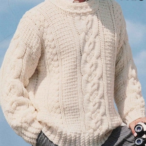 Könnte beinhalten: Ein cremeweißer, langärmeliger Pullover mit Rundhalsausschnitt, der ein markantes vertikales Zopfstrickmuster mit strukturierten Einsätzen kombiniert. Das Kleidungsstück ist grob gestrickt und verfügt über gerippte Bündchen und einen gerippten Saum.