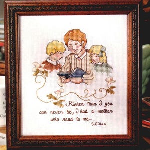 May include: Cross-stitch artwork in a dark wooden frame. The image depicts a mother reading to two children. The text reads, "Richer than I you can never be, I had a mother who read to me." by S. Gillan.