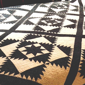 May include: A black and white quilt with a geometric pattern of stars and diamonds. The quilt is made of cotton fabric and has a quilted texture.