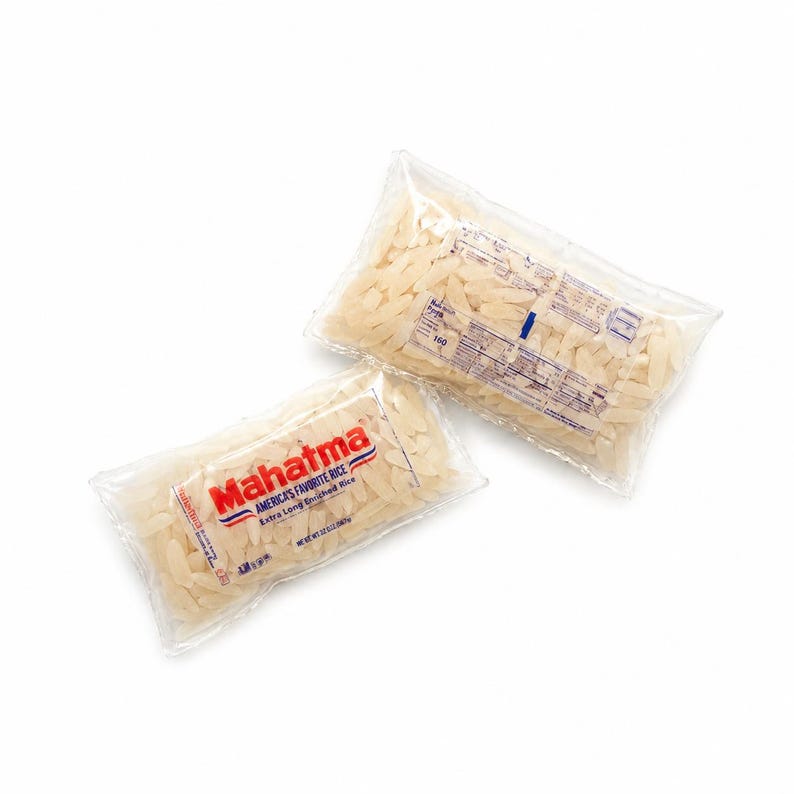 May include: Two clear plastic bags filled with Mahatma brand extra long enriched white rice. The front bag displays the red Mahatma logo, the text America's Favorite Rice, and a net weight of 32 ounces. The back bag shows nutritional information.