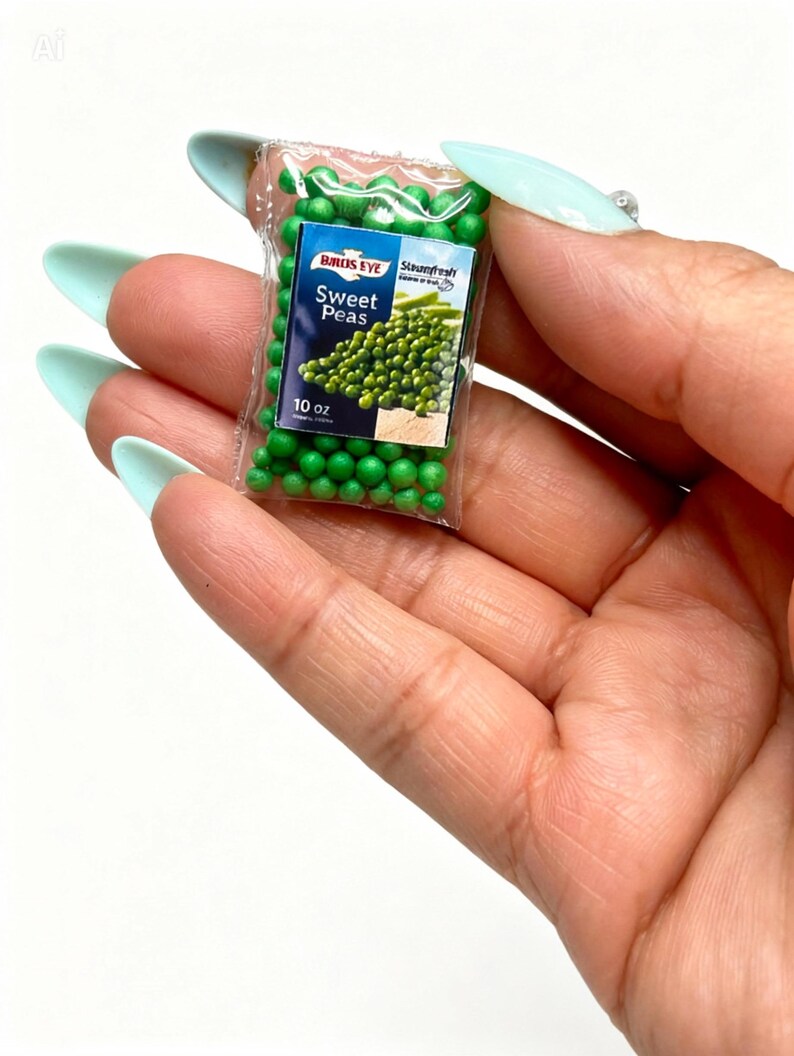 K&ouml;nnte beinhalten: Miniaturbeutel mit Birds Eye Sweet Peas, ca. 283 Gramm. Der transparente Plastikbeutel enth&auml;lt kleine gr&uuml;ne Erbsen und ein Etikett mit dem Birds Eye-Logo und den Worten "Sweet Peas". Der Beutel wird in einer Hand mit hellblauen N&auml;geln gehalten.