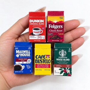 May include: Five miniature coffee product boxes featuring Dunkin Original Blend in red, Folgers Classic Roast in red and yellow, Maxwell House Original Roast in blue, Cafe Bustelo in yellow, and Starbucks House Blend in green with white text.