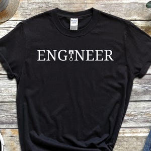 May include: Black t-shirt with white text that reads "ENGINEER" and a small wrench graphic.