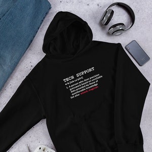 Op de afbeelding: Zwart hoodie met witte tekst die "TECH SUPPORT" luidt en een definitie van de term. De definitie bevat de uitdrukking "wizard, magician".