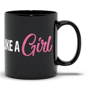 May include: Black ceramic coffee mug with the text "Play Like A Girl" in white and pink lettering.
