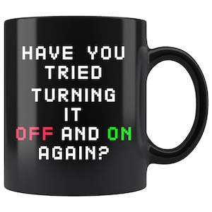 Könnte beinhalten: Schwarze Kaffeetasse mit dem Text "Haben Sie versucht, es aus- und wieder einzuschalten?" in weißer Pixel-Schrift. Die Wörter "off" und "on" sind rot bzw. grün.