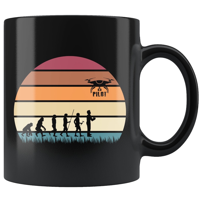 May include: Black coffee mug with a retro sunset design featuring a silhouette of a drone pilot and the evolution of man. The drone pilot is holding a remote control and the drone is flying above the sunset. The text "Drone Pilot" is printed on the mug.