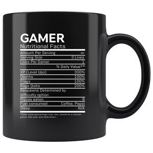 May include: Black coffee mug with a white graphic of a nutritional facts label for gamers. The label includes categories like XP (Level Ups), Deaths, Frags, Rage Quits, Pizzas Eaten, Fuel Consumed, and Sleep. The label states that the daily value percentage may vary based on a chosen gamer diet plan and dedication.