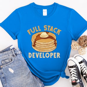 K&ouml;nnte beinhalten: Ein blaues T-Shirt mit einer Grafik eines Stapels Pfannkuchen und dem Text "Full Stack Developer".