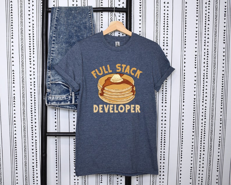 K&ouml;nnte beinhalten: Ein dunkelblaues T-Shirt mit einer Grafik eines Stapels Pfannkuchen mit Butter und Sirup. Der Text "Full Stack Developer" ist unter den Pfannkuchen gedruckt.