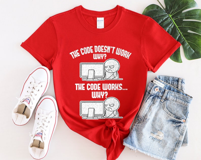 Peut inclure: T-shirt rouge avec du texte blanc qui dit "Le code ne fonctionne pas... Pourquoi ? Le code fonctionne... Pourquoi ?" Le texte est accompagn&eacute; d'une illustration de dessin anim&eacute; d'une personne devant un ordinateur.