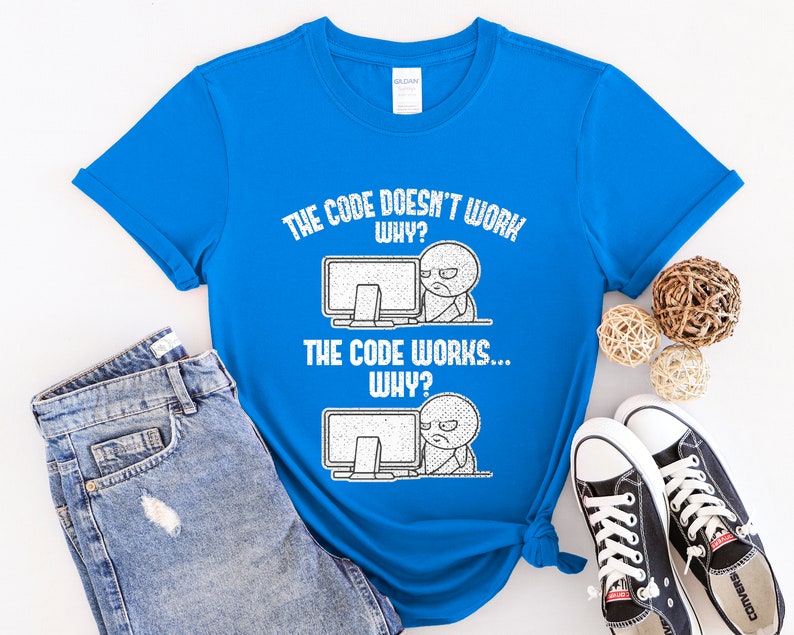 Peut inclure: Un t-shirt bleu avec un imprim&eacute; graphique blanc qui dit "The code doesn't work... Why? The code works... Why?" Le graphique repr&eacute;sente un personnage de dessin anim&eacute; avec un &eacute;cran d'ordinateur.