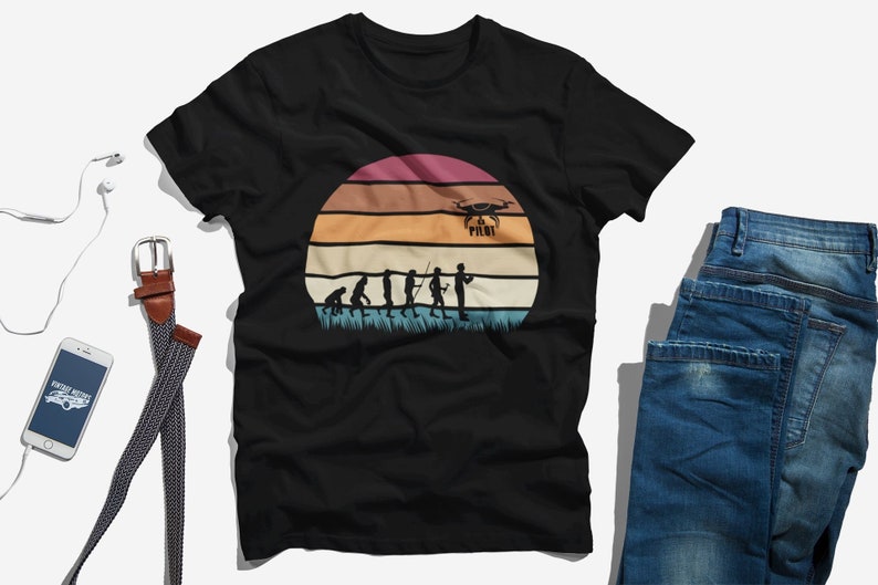 May include: Black t-shirt with a vintage-style graphic of a sunset and the evolution of man, culminating in a person holding a drone with the text "Drone Pilot".
