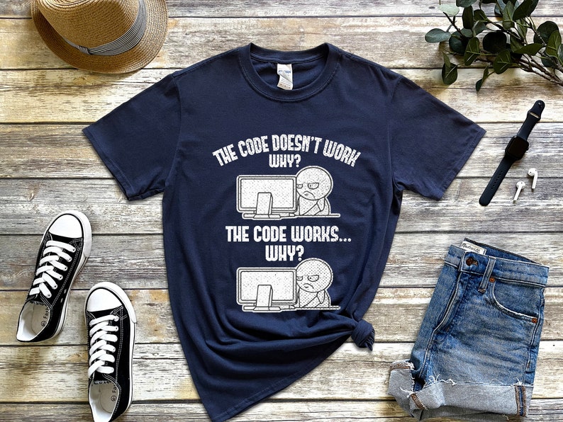 Peut inclure: Un t-shirt bleu marine avec un graphique blanc d'un &eacute;cran d'ordinateur et un bonhomme b&acirc;ton. Le texte sur le t-shirt est "The code doesn't work. Why? The code works... Why?"
