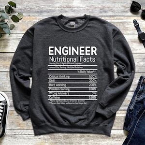 Peut inclure: Un sweat-shirt gris foncé avec un graphique blanc qui indique "ENGINEER Nutritional Facts" et liste diverses compétences avec des pourcentages. Le graphique est stylisé comme une étiquette nutritionnelle.