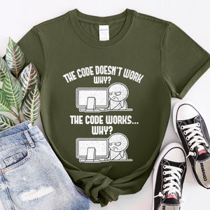 Peut inclure: Un t-shirt vert avec un imprim&eacute; graphique blanc qui dit "Le code ne fonctionne pas... Pourquoi ?" et "Le code fonctionne... Pourquoi ?" avec une illustration de dessin anim&eacute; d'une personne devant un ordinateur.