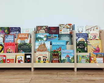 May include: A wooden bookshelf with multiple shelves filled with colorful children's books. The books have various titles in Polish, including "Basia", "Koala", "Gerda", "Wiewiórka", and "Smok".