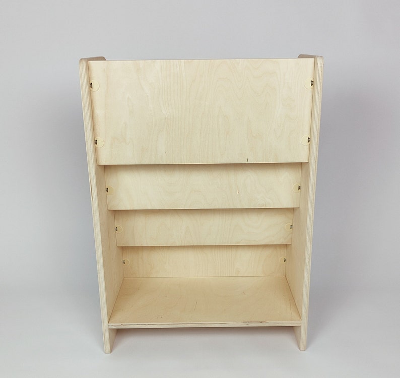 Pu&ograve; includere: Una libreria in legno chiaro con quattro ripiani. I ripiani sono in compensato e hanno una finitura naturale.