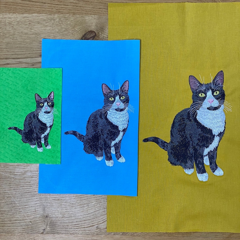 May include: Three different fabric tea towels with an embroidered black and white cat design. The towels are green, blue, and yellow.