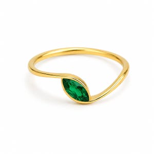 Op de afbeelding: Een gouden ring met een enkele, in marquise geslepen groene edelsteen, gezet in een gebogen, open ringband. Het metaal heeft een gepolijste afwerking en de levendige groene steen vormt het middelpunt van dit strakke sieraadontwerp.