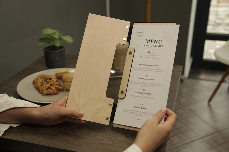 May include: A wooden menu holder with a clear acrylic insert. The menu is printed with the text "MENU restaurant-bar" and lists various food items with prices.
