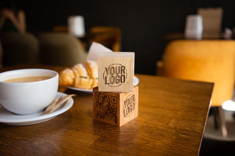 May include: Two wooden blocks stacked on top of each other. The top block has the text "YOUR LOGO" engraved on it. The bottom block has a QR code and the text "YOUR LOGO" engraved on it.
