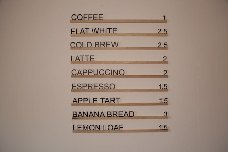 K&ouml;nnte beinhalten: Eine Speisekarte mit Preisen f&uuml;r Kaffee, Espresso-Getr&auml;nke und Backwaren. Die Preise sind in Euro angegeben. KAFFEE 1&euro;, FLATTER WEISS 2,50&euro;, KALTER BRUH 2,50&euro;, LATTE 2&euro;, CAPPUCCINO 2&euro;, ESPRESSO 1,50&euro;, APFELTARTE 1,50&euro;, BANANENBROT 3&euro;, ZITRONENKUCHEN 1,50&euro;