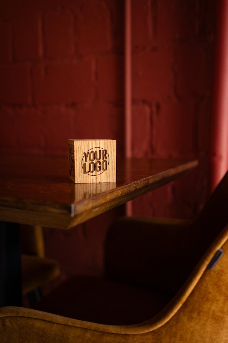 May include: A wooden block with the text "YOUR LOGO" engraved on it. The block is sitting on a wooden table in front of a red brick wall.