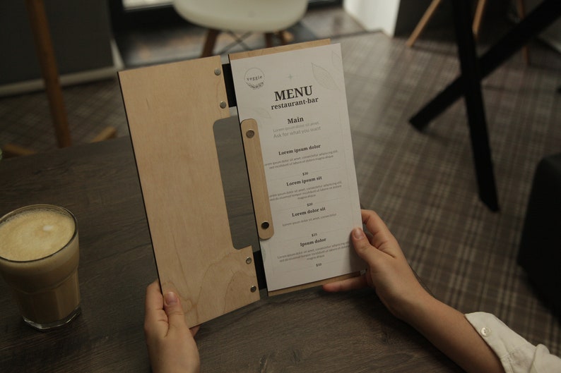 May include: A wooden menu holder with a white paper menu insert. The menu is titled "MENU restaurant-bar" and lists "Main" with several food items and prices.