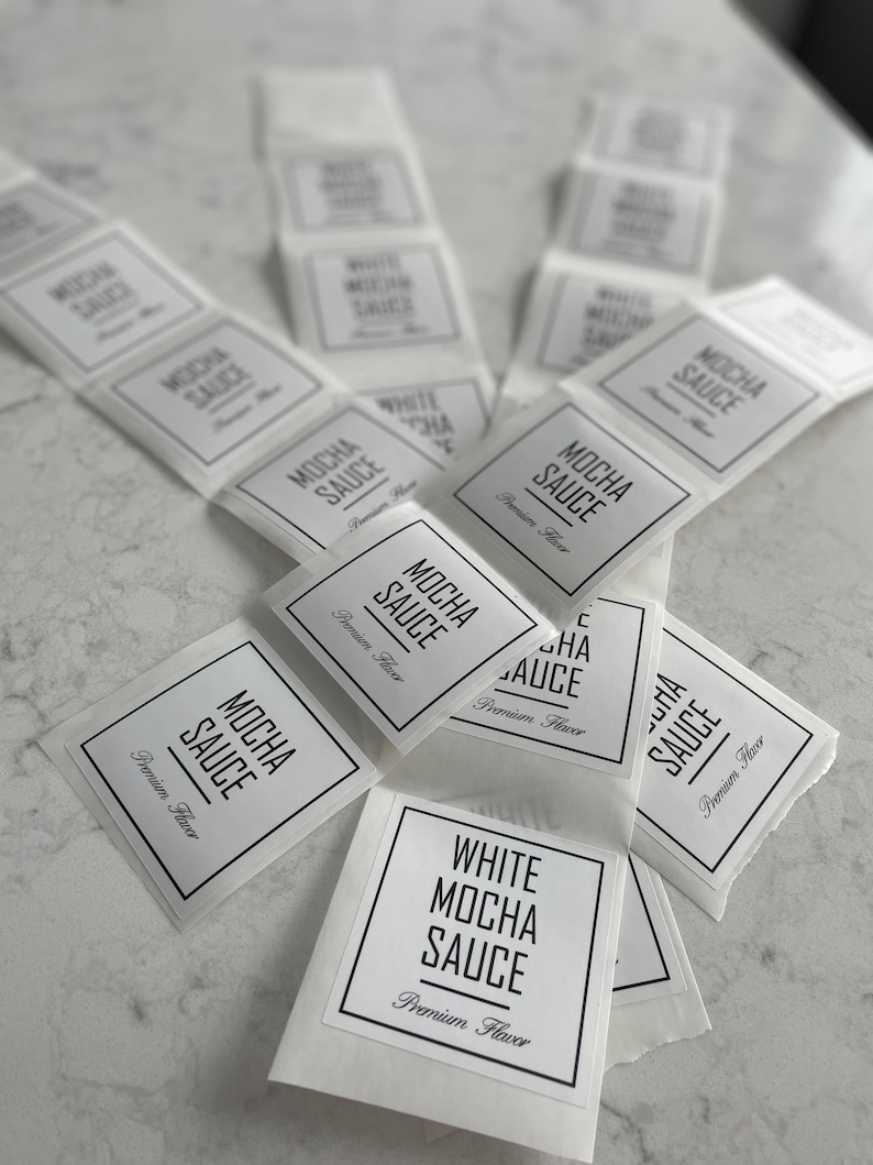 May include: A stack of white labels with black text that reads "Mocha Sauce" and "White Mocha Sauce" with the words "Premium Flavor" printed below.