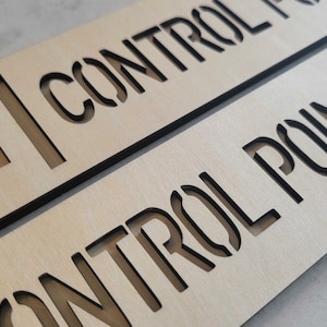 Puede incluir: Dos letreros de madera con letras negras. El letrero superior dice "CONTROL POINT" con una flecha apuntando hacia la izquierda. El letrero inferior dice "CONTROL POINT" con una flecha apuntando hacia la derecha.