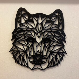 May include: Black geometric wolf head wall art made of wood. The wolf's head is made up of many triangles and is a modern and minimalist design.