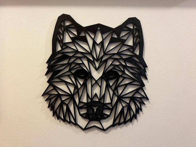 May include: Black geometric wolf head wall art made of wood. The wolf's head is made up of many triangles and is a modern and minimalist design.