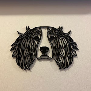 May include: Black and white geometric silhouette of a dog's head with floppy ears. The dog's face is white and the ears are black.