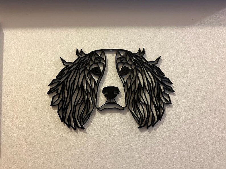 May include: Black and white geometric silhouette of a dog's head with floppy ears. The dog's face is white and the ears are black.