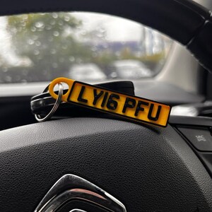 May include: A yellow car key chain with a black license plate that reads "LY16 PFU".