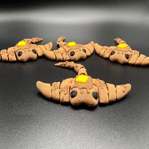 May include: Four brown and black ceramic stingray figurines with yellow accents. Each figurine has a small yellow circle on its back.