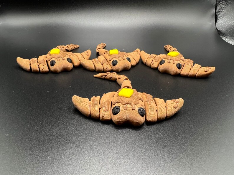 May include: Four brown and black ceramic stingray figurines with yellow accents. Each figurine has a small yellow circle on its back.
