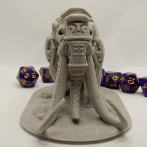 May include: A gray 3D printed miniature of a mammoth with a detailed head and tusks. The mammoth is standing on a round base.